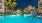 evening view of pool with lights and palm trees