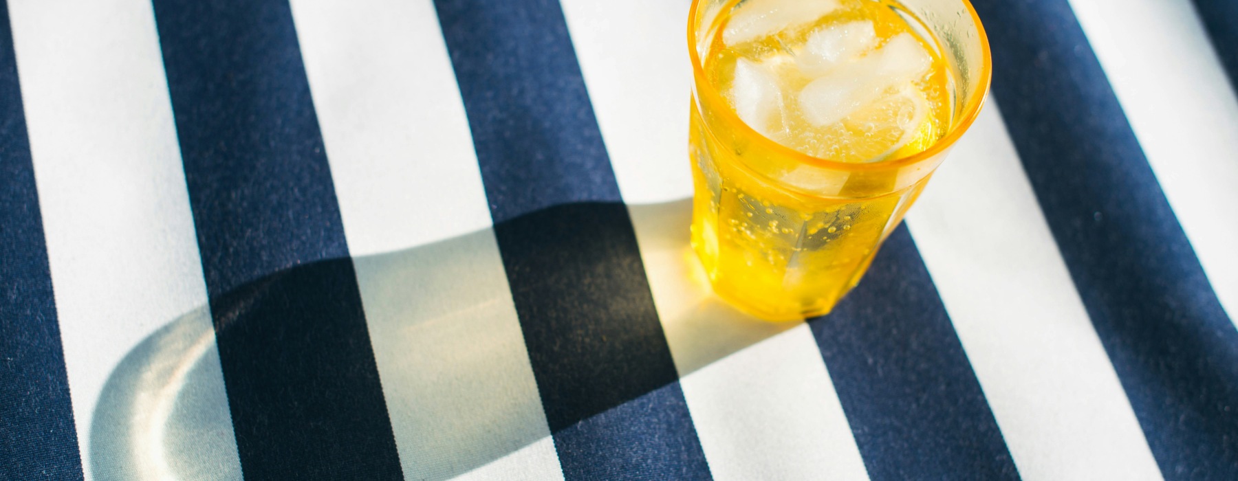 cup of iced tea on blue and white striped blanket