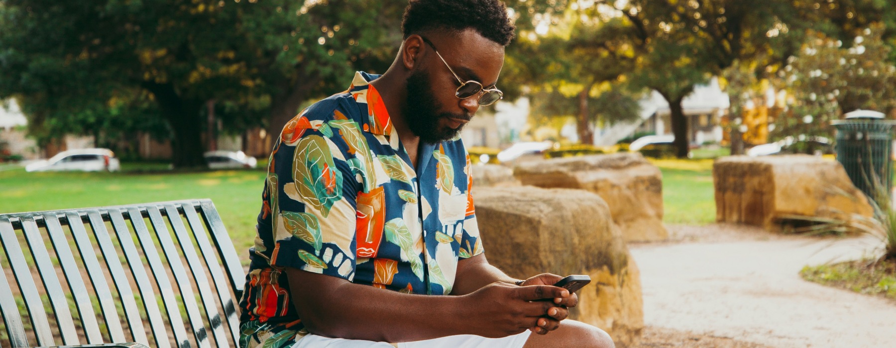 man sitting on park bench with mobile phone